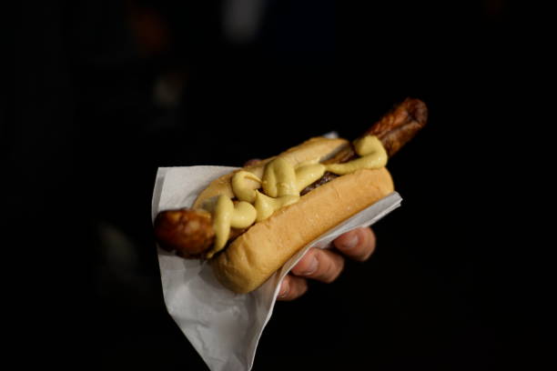 A pair of delicious Viennese sausages with Kaisersemmel, mustard and horseradish on a white paper plate. A blue patterned cloth napkin serves as the base.
