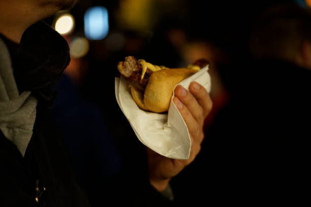 istock Hand holding a Bratwurst with mustard by night 1049047440