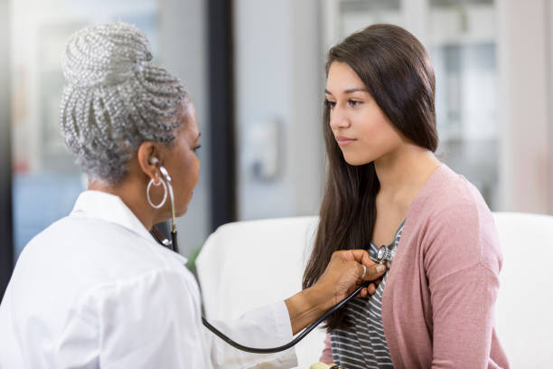 Doctor examines teenage patient Female doctor uses stethoscope to listen to teenage girl's heartbeat. womens issues photos stock pictures, royalty-free photos & images