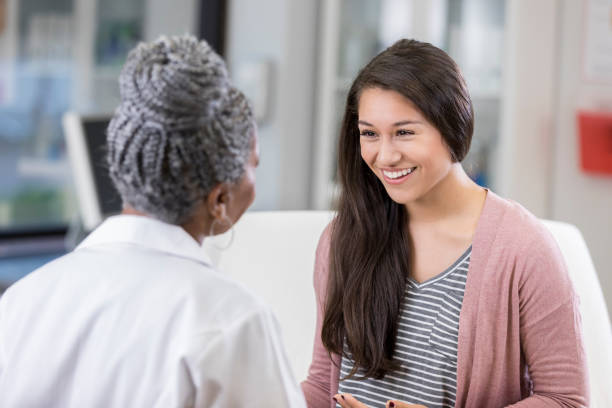 wesoły pacjent rozmawia z kobietą lekarza - doctor patient doctors office teenager zdjęcia i obrazy z banku zdjęć