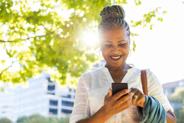 istock Confident woman uses smartphone in park 1049053802