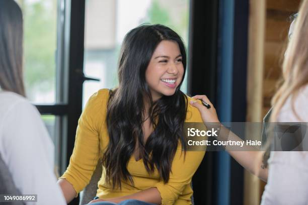 Mujer Hispana Sonriente Durante La Reunión De Grupo De Terapia De Apoyo Foto de stock y más banco de imágenes de Terapia de grupo