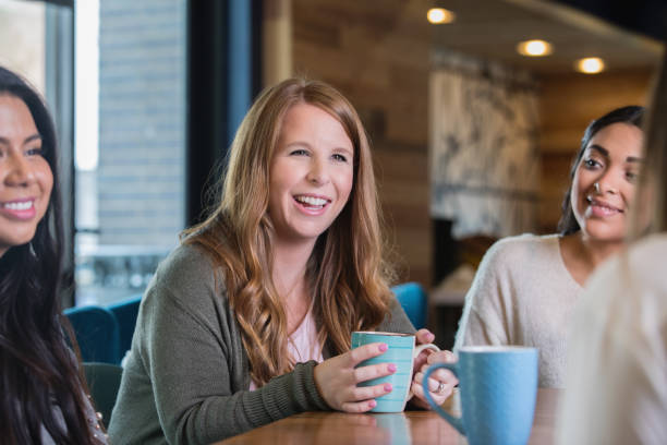 Diverse group of female friends having coffee together during meetup stock photo