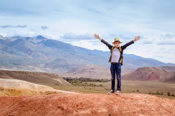 istock Happy boy traveler with his hands up on blue mountains background 1049100884