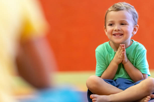 bambino seduto sul pavimento durante la lezione di yoga per bambini - top of the class foto e immagini stock