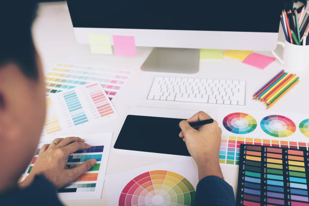 istock Rear view of creative designers working on desk using digital graphic tablet and drawing with pen in modern home office. 1049120534