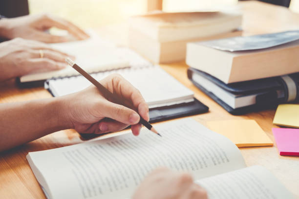 istock High school or college students studying and reading together in library 1049123268
