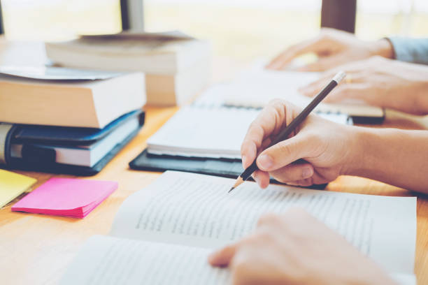 istock High school or college students studying and reading together in library 1049123280