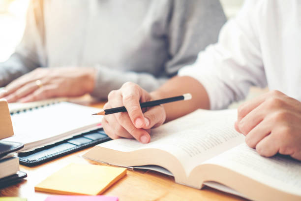 istock High school or college students studying and reading together in library 1049123288