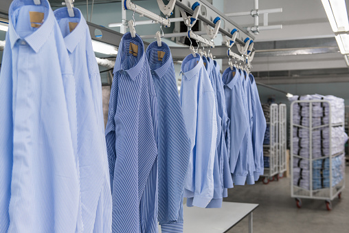 sewn new shirts hang on hangers in the textile factory workshop