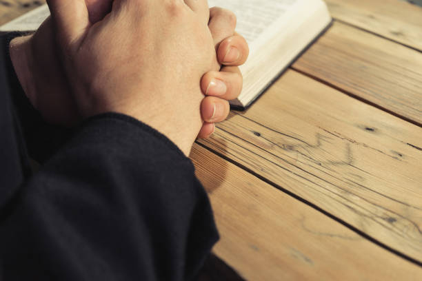 istock Man sitting at a old oak table reading the Holy Bible 1049171442