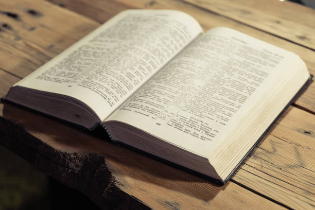 istock Man sitting at a old oak table reading the Holy Bible 1049171798