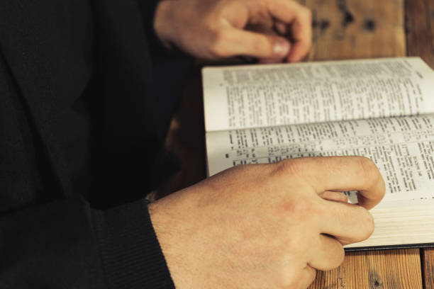 istock Man sitting at a old oak table reading the Holy Bible 1049174364