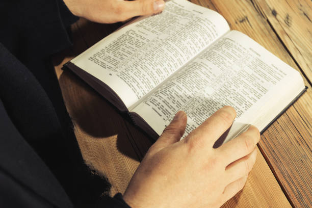 istock Man sitting at a old oak table reading the Holy Bible 1049180604