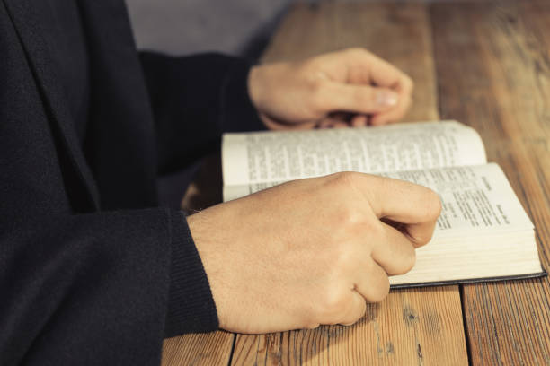 istock Man sitting at a old oak table reading the Holy Bible 1049186412