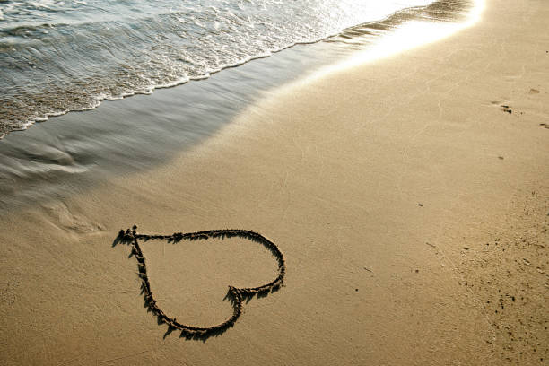istock Close up heart shape drawing on sandy beach 1049186604