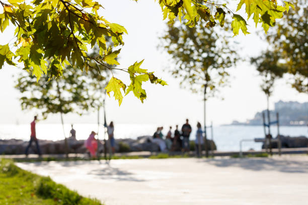 Youth people are sitting at sea coast of The Kadikoy - Kalamis with beautiful reflections on the water at sunset.