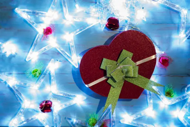 Top view of Christmas gift shaped heart with Christmas star lights on the wooden table