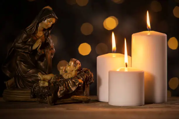 Christmas scene of virgin Mary with baby Jesus and glowing candles on the table