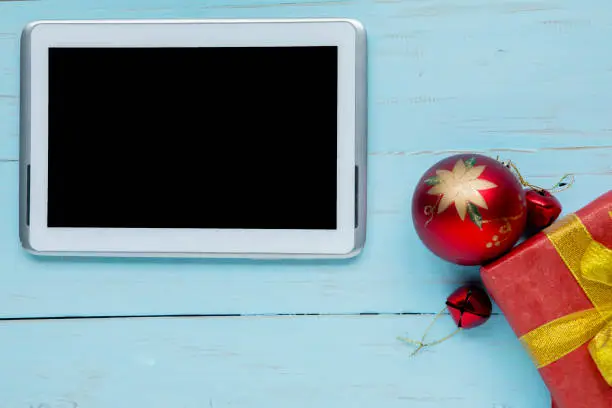 Top view of digital tablet with Christmas ball and gift box on the wooden table