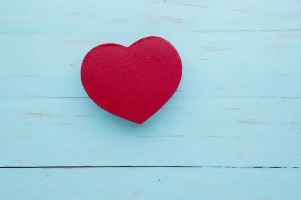 Picture of red gift box shaped a heart symbol on the wooden table