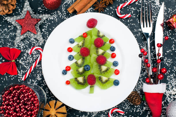 istock Kiwi christmas tree with raspberry, blueberry and cowberry on table with decoration 1049201850