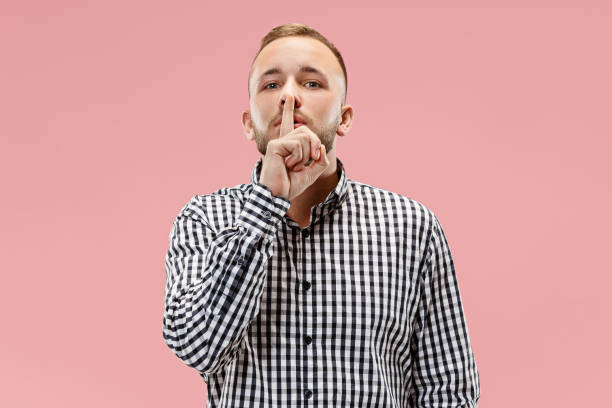 istock The young man whispering a secret behind her hand over pink background 1049202122