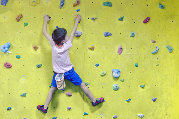 istock Free climber child young boy practicing on artificial boulders in gym, bouldering 1049204362