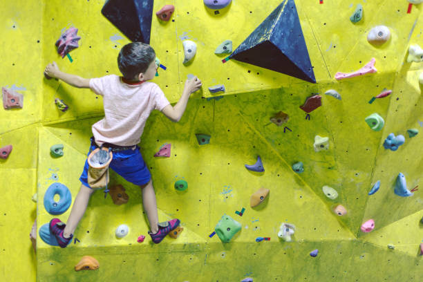 istock Free climber child young boy practicing on artificial boulders in gym, bouldering 1049204372