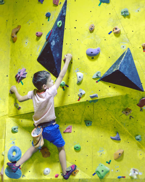 istock Free climber child young boy practicing on artificial boulders in gym, bouldering 1049204376
