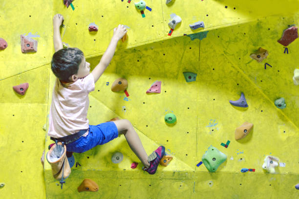 istock Free climber child young boy practicing on artificial boulders in gym, bouldering 1049204382