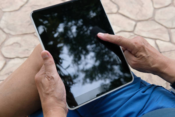 istock man holding tablet. hand texting message, using app with touchpad outdoor 1049210730