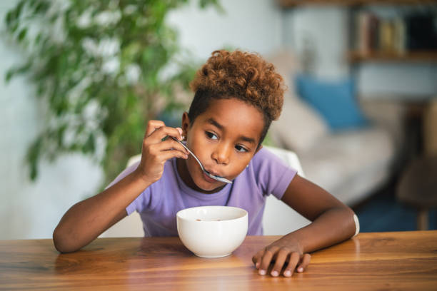 African girl eating cereals Cute African girl is having cereal breakfast at home. black people eating stock pictures, royalty-free photos & images