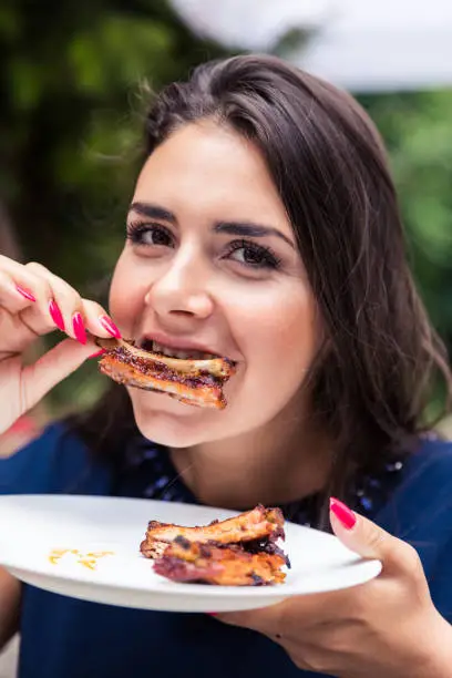 Hungry woman enjoying in taste of bbq grilled pork ribs.