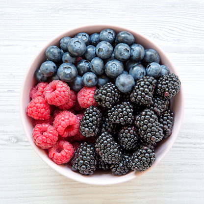 Pink bowl of fresh berries: blackberry, raspberry, blueberry, overhead view. Summer berry. From above, overhead. Close-up.