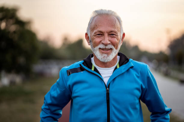Portrait of active senior man smiling Active senior man is looking at camera and smiling on the running track outdoors. medium shot stock pictures, royalty-free photos & images