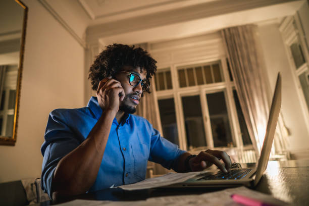 istock Male student using laptop and talking on cellphone 1049217332
