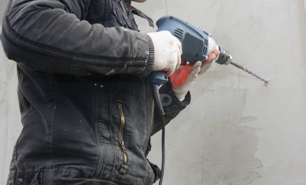 istock Contractor drilling plaster wall to install rain gutter downspout pipe holder. 1049220394
