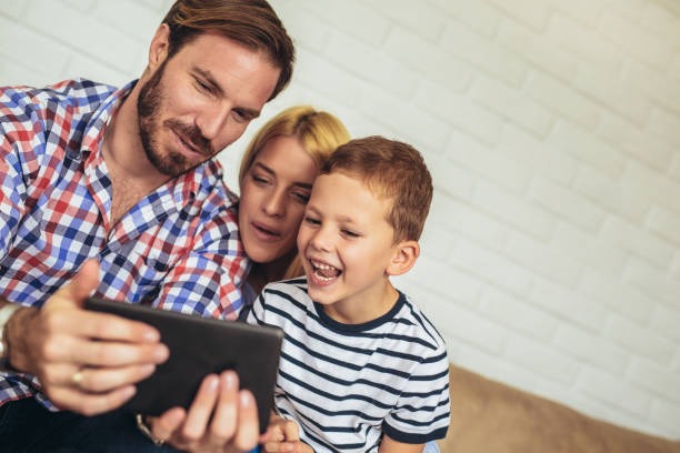 istock Happy family using digital tablet taking selfie at home 1049220494