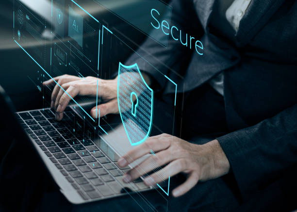 A person in a suit is typing on a laptop, with a translucent display showing a digital shield and a lock icon, accompanied by the word "Secure" in a modern font.