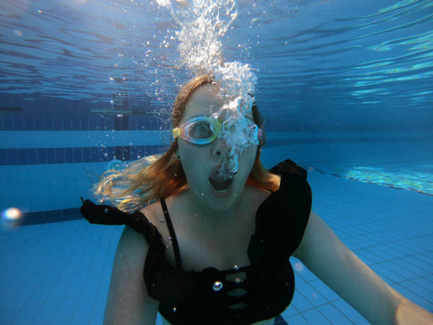 Young woman diving in swimming pool stock photo