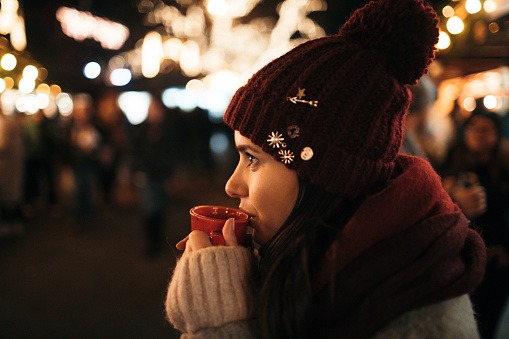 Young woman drinking mulled wine at Christmas market