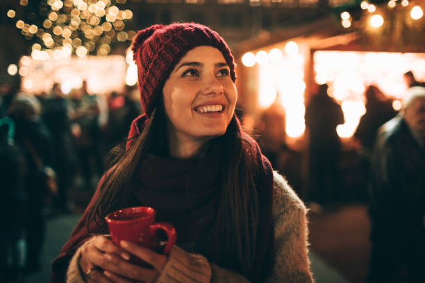 genieten van glühwein op kerstmarkt - christmas people stockfoto's en -beelden