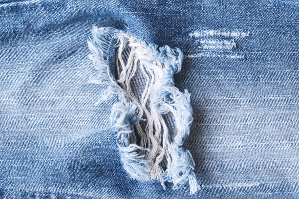 trou et fil bleu jeans en denim, déchirés jeans déchirés texture. - textile canvas torn textured photos et images de collection