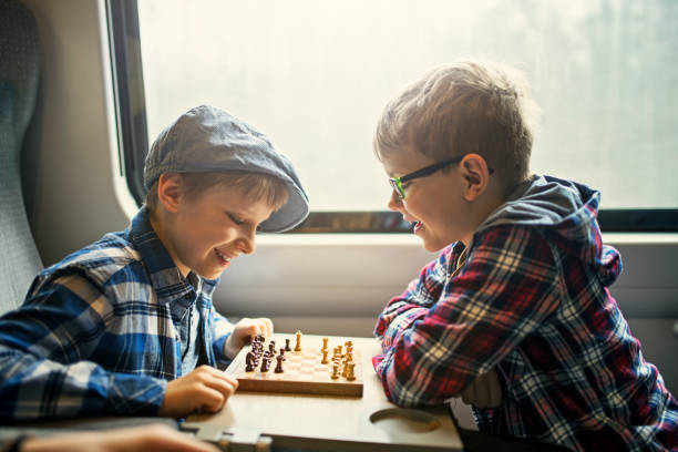 Little boys enjoying train journey. Brothers are playing chess.Nikon D850