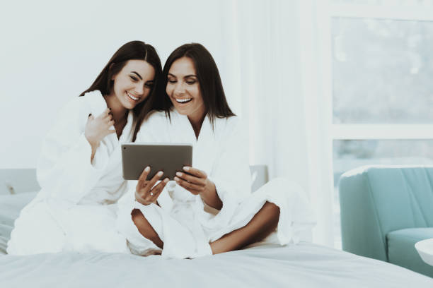 istock Girls In A Bathrobes Are Looking At Tablet Screen. 1049231140