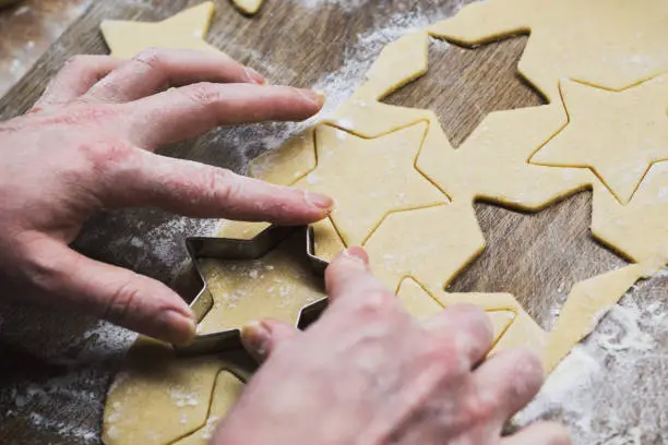 Christmas baking. Woman making gingerbread biscuits. Hand detail.