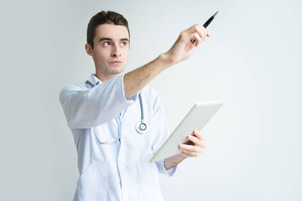 istock Serious male doctor holding tablet and pointing aside 1049237202