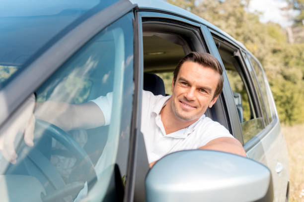 istock happy man looking out window while driving car in field 1049237484