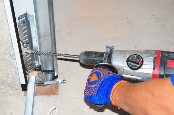 istock Contractor  repair and install garage door with drilling machine. Replace a broken garage door spring. 1049237720